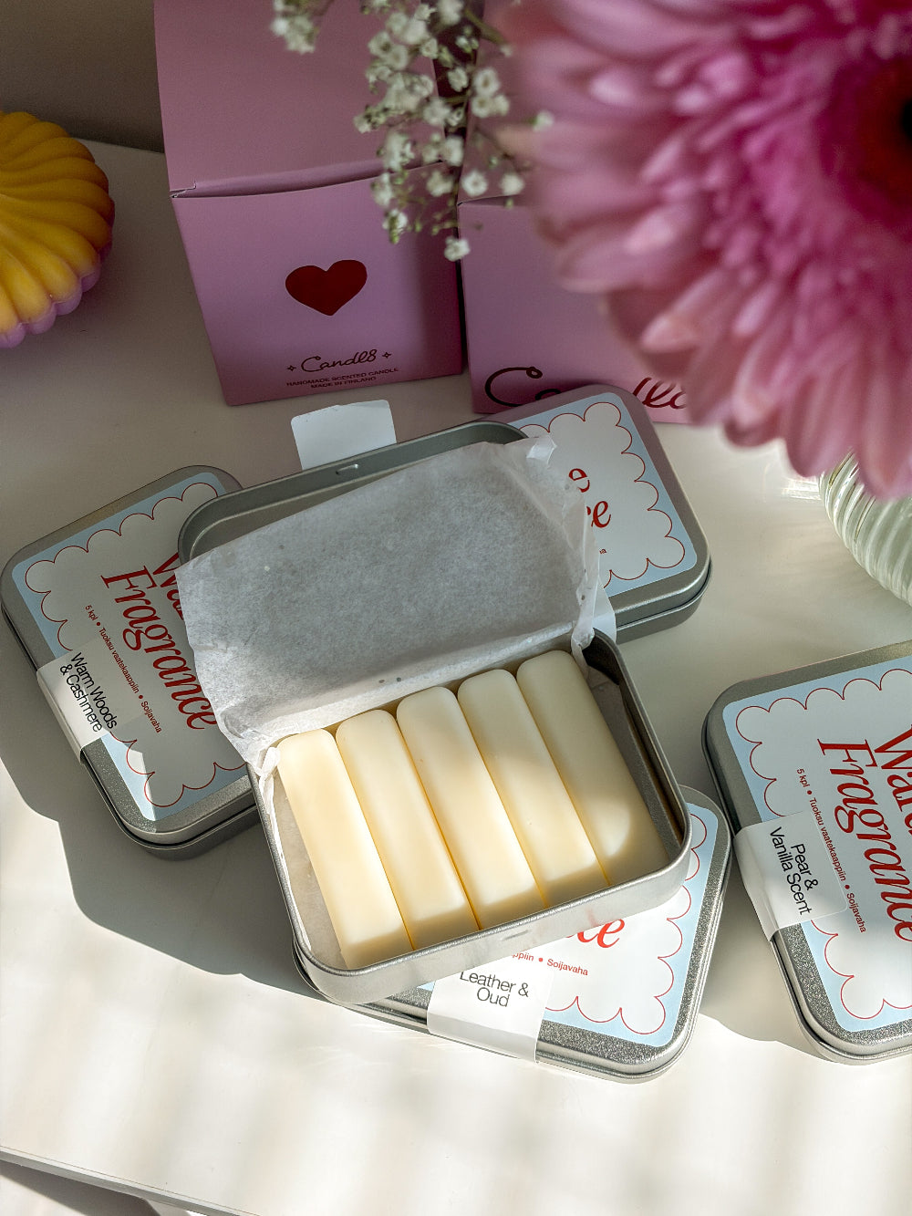 Small metal tin with white bars of soap, pink box with heart design in the background