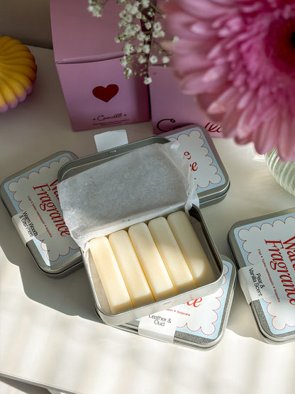 Small metal tin with white bars of soap, pink box with heart design in the background